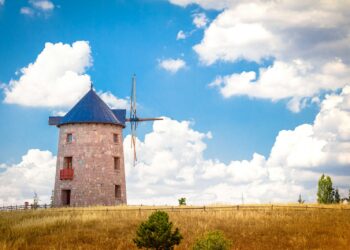 brown brick building under blue sky and white clouds during daytime