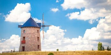 brown brick building under blue sky and white clouds during daytime
