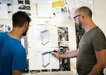 man in blue crew neck t-shirt holding white printer paper