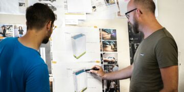 man in blue crew neck t-shirt holding white printer paper