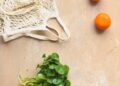 three oranges and a bag of greens on a table