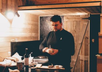 man in black dress shirt standing in front of table