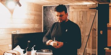 man in black dress shirt standing in front of table