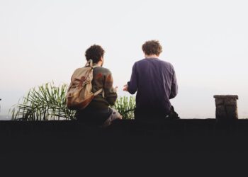 man and woman sitting on brown wooden bench during daytime