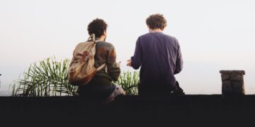 man and woman sitting on brown wooden bench during daytime