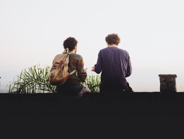 man and woman sitting on brown wooden bench during daytime