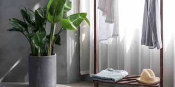 gray dress shirt hang on brown wooden rack in front of window with white curtain