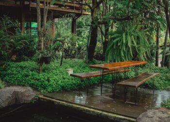 a pond with a bench and a gazebo in the background