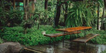 a pond with a bench and a gazebo in the background