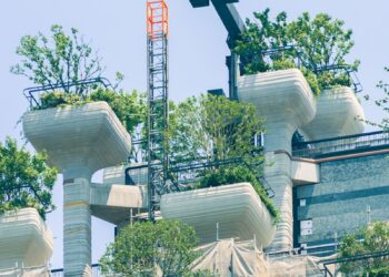 Modern building with green rooftop gardens and scaffolding.