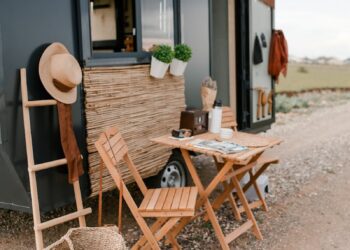 Rustic outdoor dining setup beside a modern tiny home with wicker baskets and wood elements.