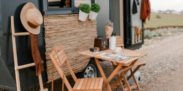 Rustic outdoor dining setup beside a modern tiny home with wicker baskets and wood elements.