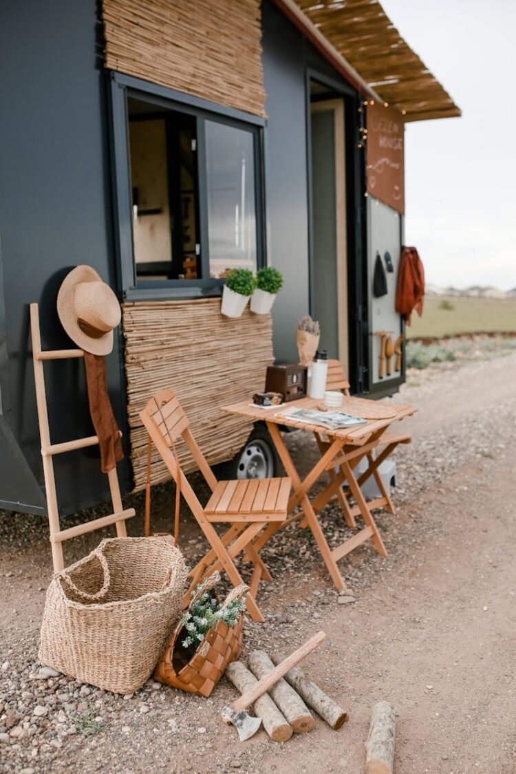 Rustic outdoor dining setup beside a modern tiny home with wicker baskets and wood elements.