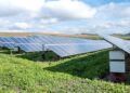 blue solar panels on green grass field under white clouds and blue sky during daytime