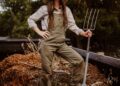 A woman in overalls and a straw hat holding a pitchfork