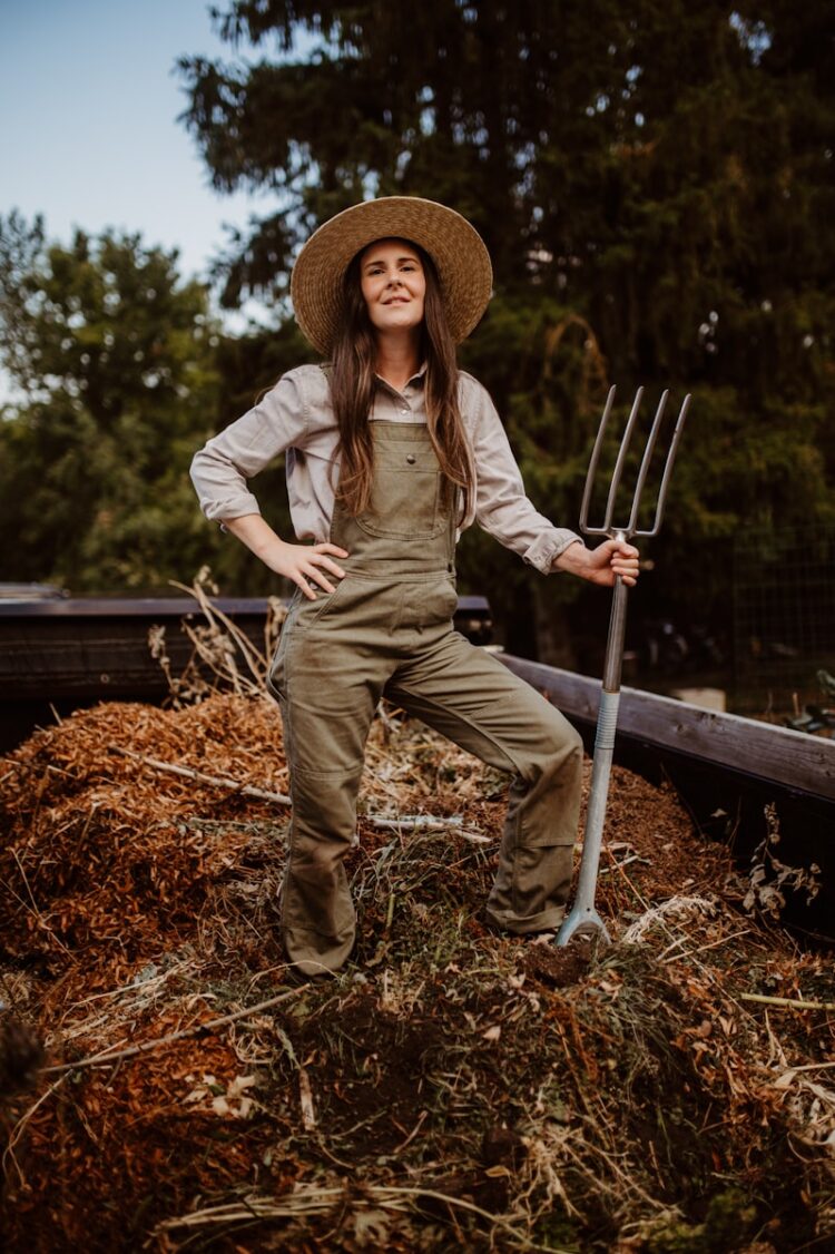 A woman in overalls and a straw hat holding a pitchfork