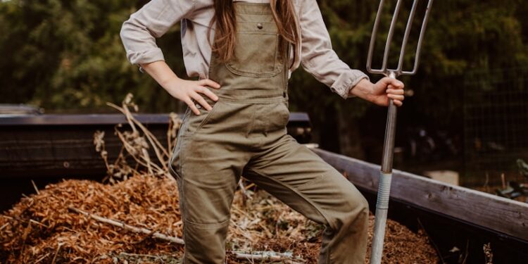A woman in overalls and a straw hat holding a pitchfork