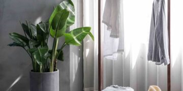 gray dress shirt hang on brown wooden rack in front of window with white curtain