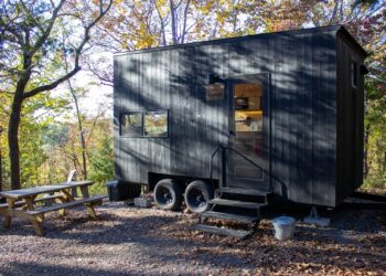 A dark tiny house with a picnic table outside.