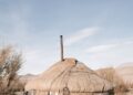 A traditional Mongolian yurt equipped with solar panels in a desert setting.