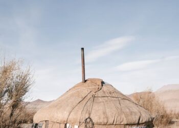 A traditional Mongolian yurt equipped with solar panels in a desert setting.