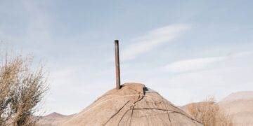 A traditional Mongolian yurt equipped with solar panels in a desert setting.