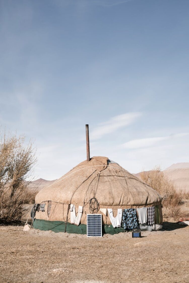 A traditional Mongolian yurt equipped with solar panels in a desert setting.