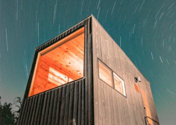 Night view of a modern tiny house illuminated under a starry sky in Wimberley, Texas.