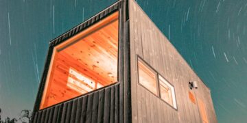 Night view of a modern tiny house illuminated under a starry sky in Wimberley, Texas.