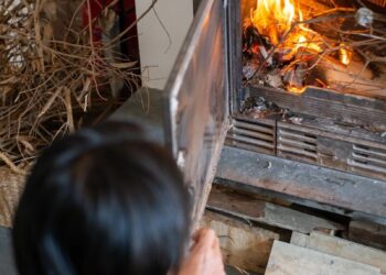 A person tends to a wood-burning fireplace, creating a warm indoor atmosphere.