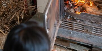 A person tends to a wood-burning fireplace, creating a warm indoor atmosphere.