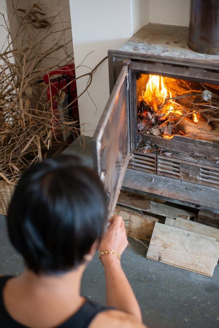 A person tends to a wood-burning fireplace, creating a warm indoor atmosphere.