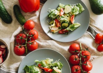 Top view of a vibrant vegetable salad featuring fresh ingredients on plates and a towel.