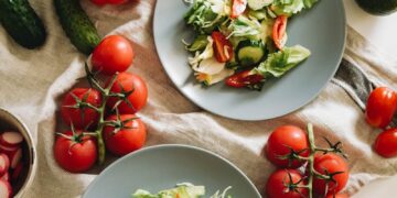 Top view of a vibrant vegetable salad featuring fresh ingredients on plates and a towel.