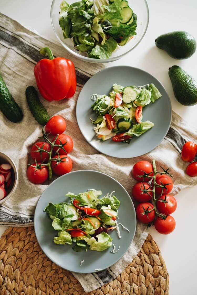Top view of a vibrant vegetable salad featuring fresh ingredients on plates and a towel.
