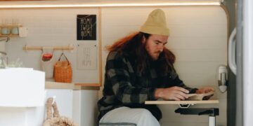 Person relaxing in a cozy camper van interior, reading a book. Perfect for van life enthusiasts.