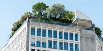 A modern building featuring lush rooftop gardens under a clear blue sky.