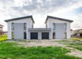 Front view of twin modern houses with a symmetrical architectural design under a cloudy sky.