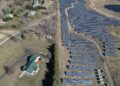 Aerial image showcasing a solar farm adjacent to a residential area in a rural setting.