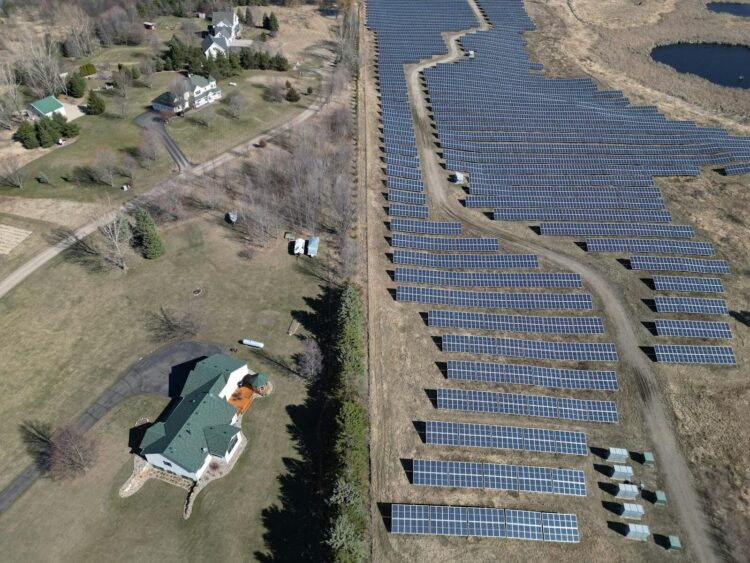 Aerial image showcasing a solar farm adjacent to a residential area in a rural setting.