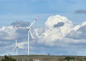 Two wind turbines in a countryside setting with a dramatic cloudy sky.