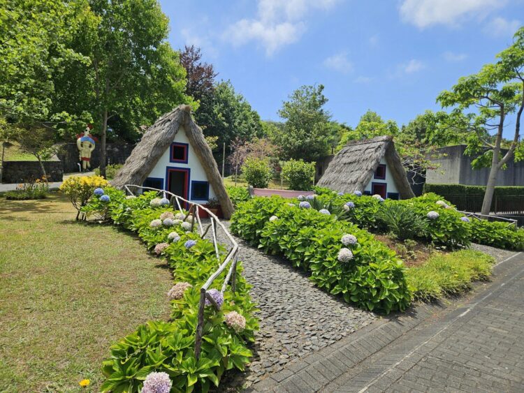 a row of thatched roofed houses in a garden