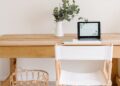Elegant minimalist home office with a wooden desk, chair, and tablet setup.