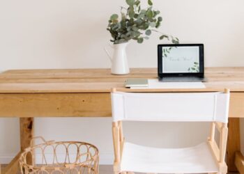 Elegant minimalist home office with a wooden desk, chair, and tablet setup.