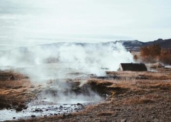 A serene geothermal field with steam rising amid autumnal surroundings. Perfect for nature and travel themes.
