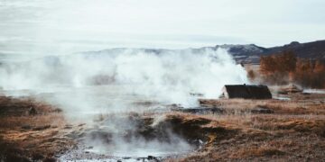 A serene geothermal field with steam rising amid autumnal surroundings. Perfect for nature and travel themes.
