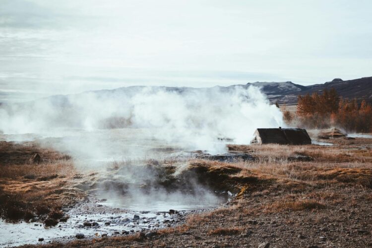 A serene geothermal field with steam rising amid autumnal surroundings. Perfect for nature and travel themes.
