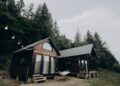 Charming wooden cabins surrounded by lush forest with string lights at dusk, creating a serene and cozy atmosphere.