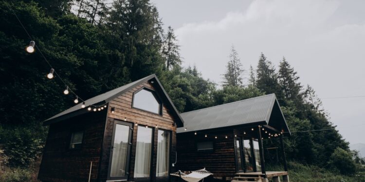 Charming wooden cabins surrounded by lush forest with string lights at dusk, creating a serene and cozy atmosphere.