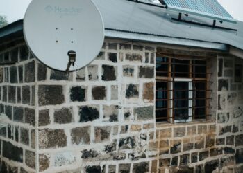 Stone exterior house with solar panel and satellite dish, showcasing sustainable energy solutions.
